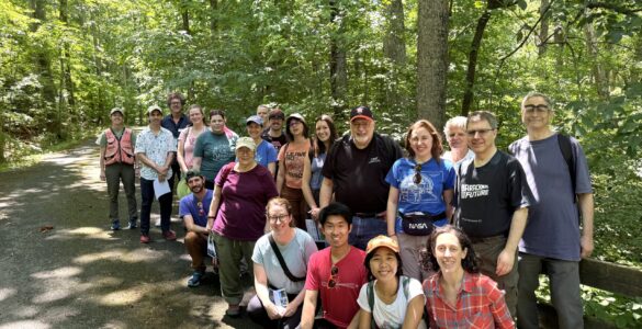 A group of 21 people outdoors on a forest path